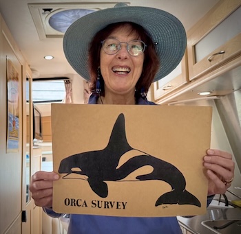 A woman holding a sign with an orca on it with text "Orca Survey"