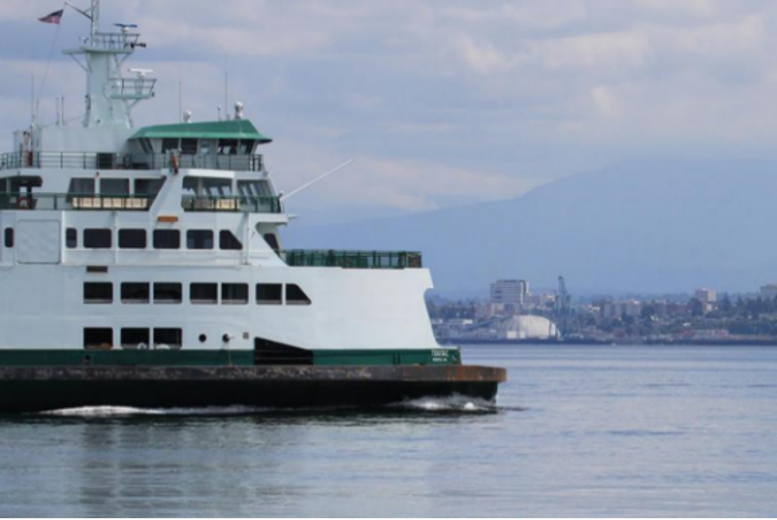 A Washington State ferry. The image of a humpback whale is barely visible near the bow of the ferry. 