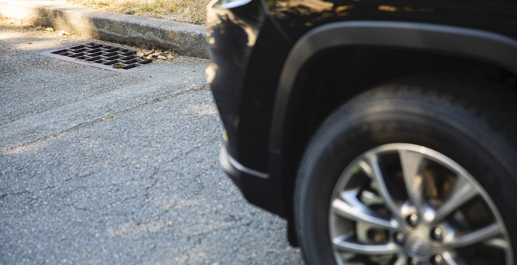 Vehicle tire on pavement near storm drain grate 