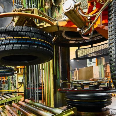 Tire manufacturing facility with l tire positioned on industrial equipment and multiple tires stacked throughout