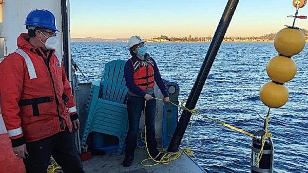 Marine technician Sony Brugger, right, retrieves underwater sampling equipment during a December 2020 research cruise aboard the RV Rachel Carson. Tor Bjorklund, left, is marine engineer and chief scientist during on the cruise off Alki Point, seen in the background. (UW photo)