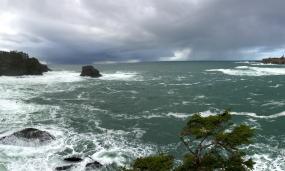 View of turbulent ocean water with rain clouds on the horizon and land to the north and south