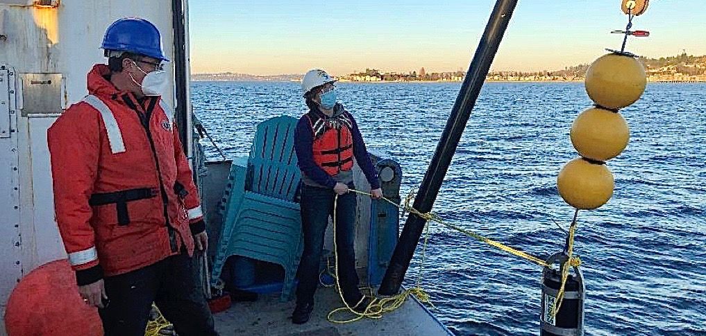 Marine technician Sony Brugger, right, retrieves underwater sampling equipment during a December 2020 research cruise aboard the RV Rachel Carson. Tor Bjorklund, left, is marine engineer and chief scientist during on the cruise off Alki Point, seen in the background. (UW photo)